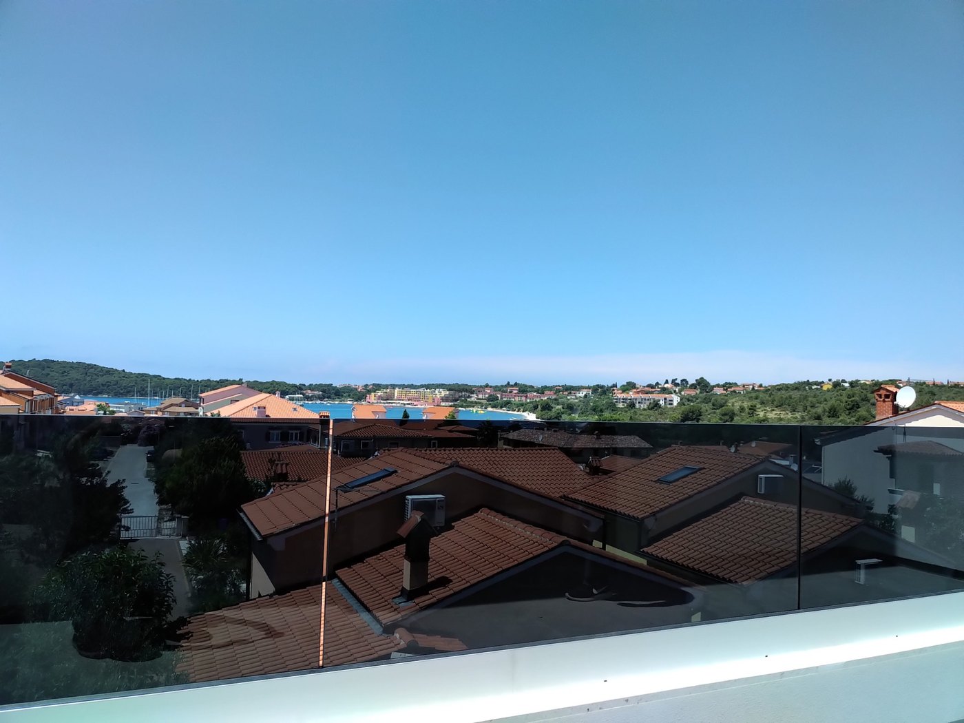 Staklena ograda od tamnosivog parsola na terasi s pogledom na more